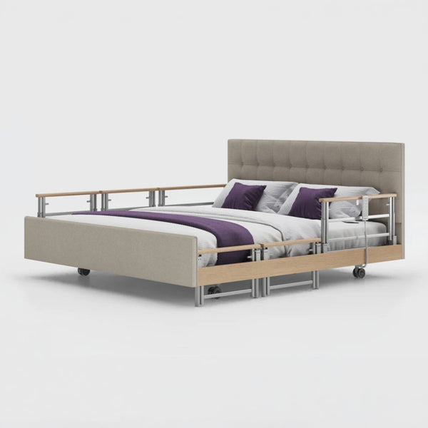 Opera Beds Signature Comfort Plus Dual Profiling Bed with drop side rails and wheels, white background, front view.