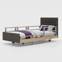 Profiling bed with wheels, side rails and leatherette cushioning, dressed in white linens, front view.