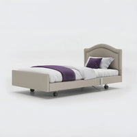 Profiling bed with white bedding, purple blanket and pillow on a plain white background, front view.