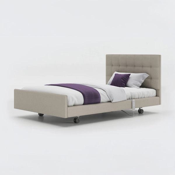 Signature Comfort Profiling Bed with tufted headboard, white bedding, purple throw and wheels, side view.