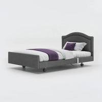 Opera Beds Signature Comfort Profiling Bed with white bedding, purple blanket, and wheels, side view.