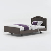 Opera Beds Signature Comfort Profiling Bed with white bedding, purple runner and wheels on a plain background, front view.