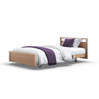 Opera Beds Signature Low Footboard Profiling Bed with white bedding, purple blanket, matching pillows, adjustable leg rest and wheels, side view.