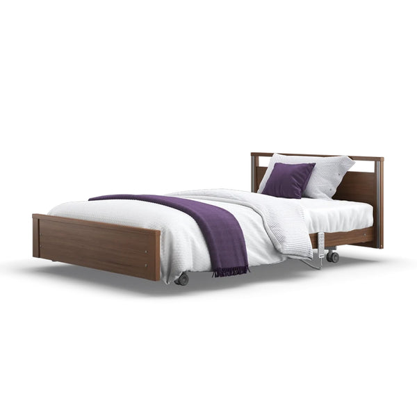 Opera Beds Signature Low Footboard Profiling Bed with white bedding, purple blanket, pillows and wheels on white background, front view.