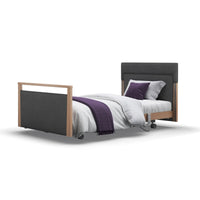 Opera Beds Signature Upholstered Profiling Bed with dark frame, white bedding and purple accent, side view.