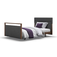 Upholstered profiling bed with white bedding, grey headboard, and purple blanket and pillow, front view.