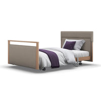 Opera Beds Signature Profiling Bed with wheels, linen, headboard, footboard, white bedding, purple blanket & pillow, front view.