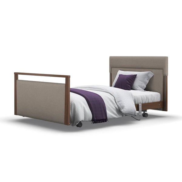 Signature Upholstered Profiling Bed in linen fabric with wheels, headboard and footboard, white bedding, purple blanket, pillows, front view.