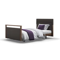 Opera Beds Signature Upholstered Profiling Bed with white bedding, purple blanket and cushions, front view.