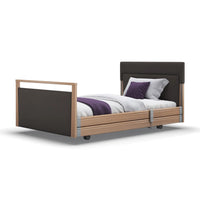 Opera Beds Signature Upholstered Profiling Bed with dark frame and headboard, white, grey, and purple bedding, front view.