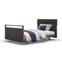 Upholstered profiling bed with dark frame, white bedding, purple accents, wheels and adjustable headrest, front view.
