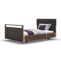 Signature Upholstered Profiling Bed with side rails, dark wood, white bedding and purple throw accents, front view.