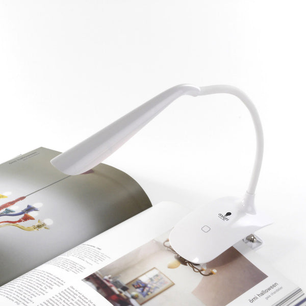 Daylight Company Smart Clip-On Lamp illuminating an open magazine on a white surface, in use view.