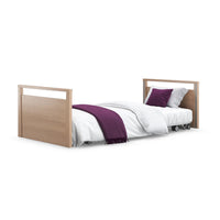 Opera Beds Solo SafeSide Profiling Floor Bed with white bedding, purple blanket and two purple pillows, side view.