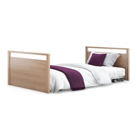 Opera Beds Solo SafeSide Floor Bed with white bedding, purple blanket and two purple pillows, side view.