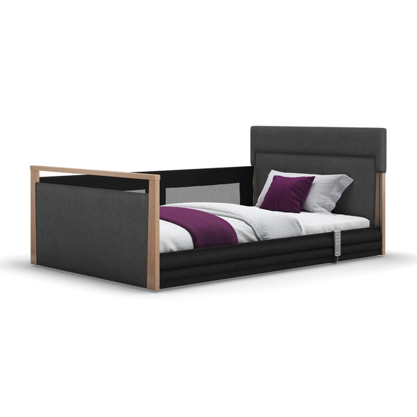 Opera Beds Solo SafeSide upholstered profiling floor bed with wooden accents, white bedding and purple accessories, side view.