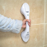 Hand holding Lifemax Stick ‘n’ Stay Grab Bar with suction cups attached to tiled bathroom wall, in use view.