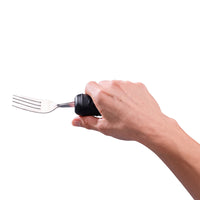 Hand holding a Homecraft Sure Grip Bendable Utensil with a large handle, white background, in use view.