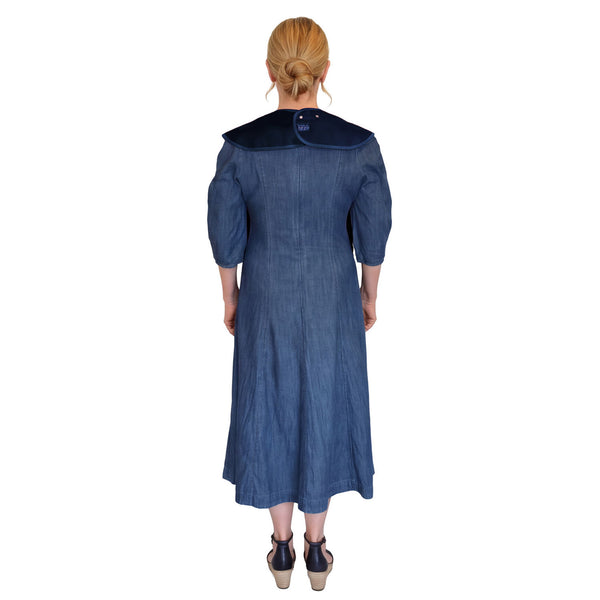 Woman in blue midi dress wearing Care Designs Tabard Style Adult Bib, blonde hair tied back, rear view.
