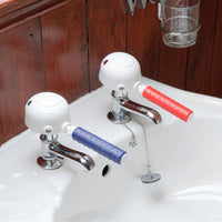 Gordon Ellis tap turners with easy-grip handles for cold and hot taps on a white basin, fitted in place, overhead view.