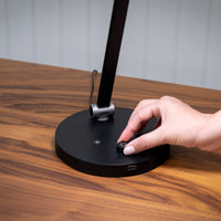Hand adjusting knob on The Daylight Companys TriSun Therapy Lamp with adjustable brightness, in use close-up.