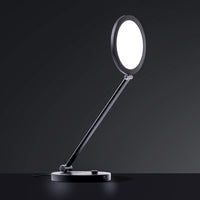 The Daylight Company TriSun Therapy Lamp with circular light and adjustable arm, dark background, angled front view.