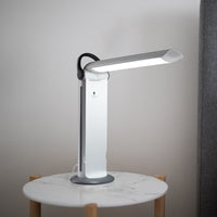Twist 2 Portable Lamp with curved arm on round marble table, light wall background, side view.