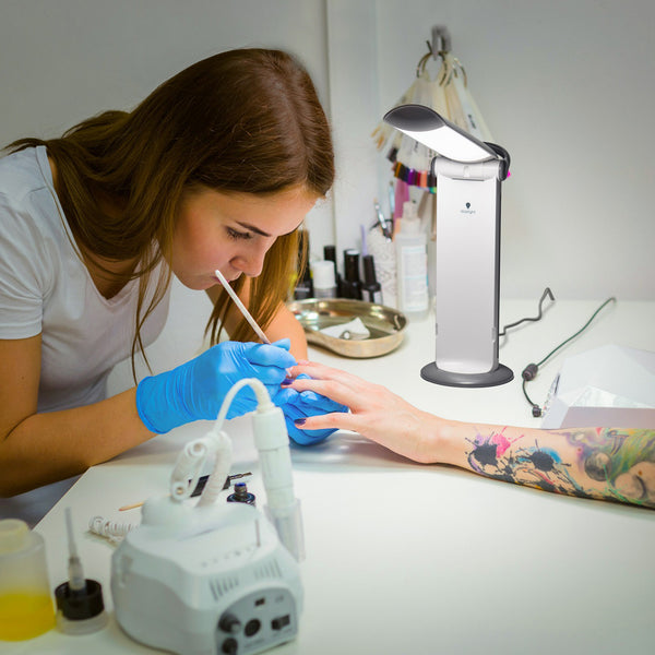 The Daylight Company Twist 2 Portable Lamp being used by a nail technician to polish a clients nails, in use.