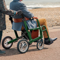 Able2 Uplivin Glide 2-in-1 Rollator and Wheelchair in use on a seaside pebble path, rear view.
