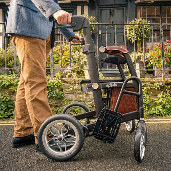 Person outdoors with Able2 Uplivin Glide 2-in-1 Rollator and Wheelchair, in use rear angle.