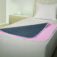 Hospital bed with grey mattress, pillow and Able2 Vida Washable Bed Pad for incontinence protection, front view.