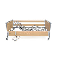 Woburn Community Bed with wooden side panels, metal frame, wheels and remote control, profiling design, angled side view.