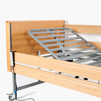 Harvest Healthcare Woburn Profiling Bed with adjustable metal slats, electric backrest and corded remote, side view.
